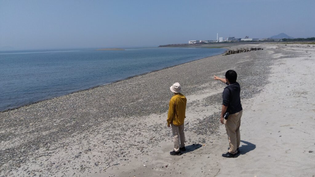 重信川河口。礫と砂の海岸線が広がる。右が田辺篤志さん。