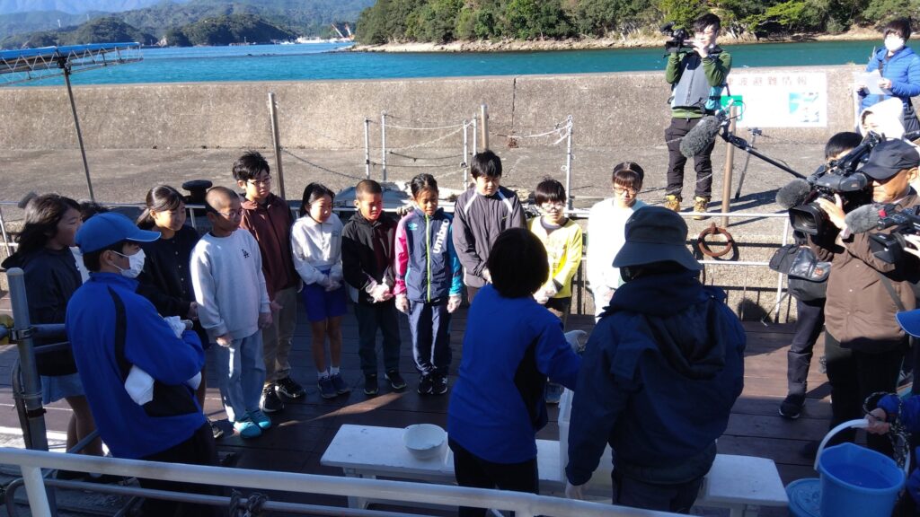 サンゴの移植活動に参加した宍喰小学校５年生。ブルーマリンの船上で、スタッフから手順についての説明を聞く。