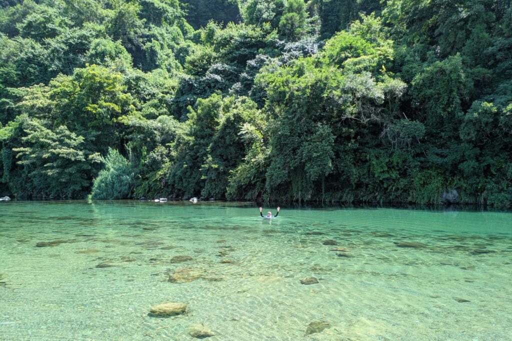 スタスタと川に入っていき、「ほら、こんなに深いよ」と、手をあげて見せる山本さん。びっくりしてみていた子どもたち。生きた環境教育！